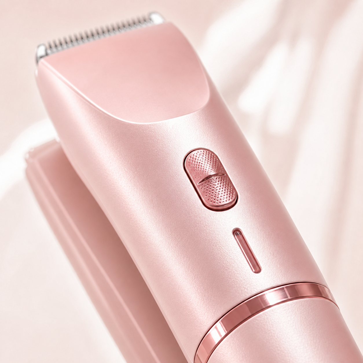 Macro close-up of textured button and rose-gold trim on the blush pink women's body shaver